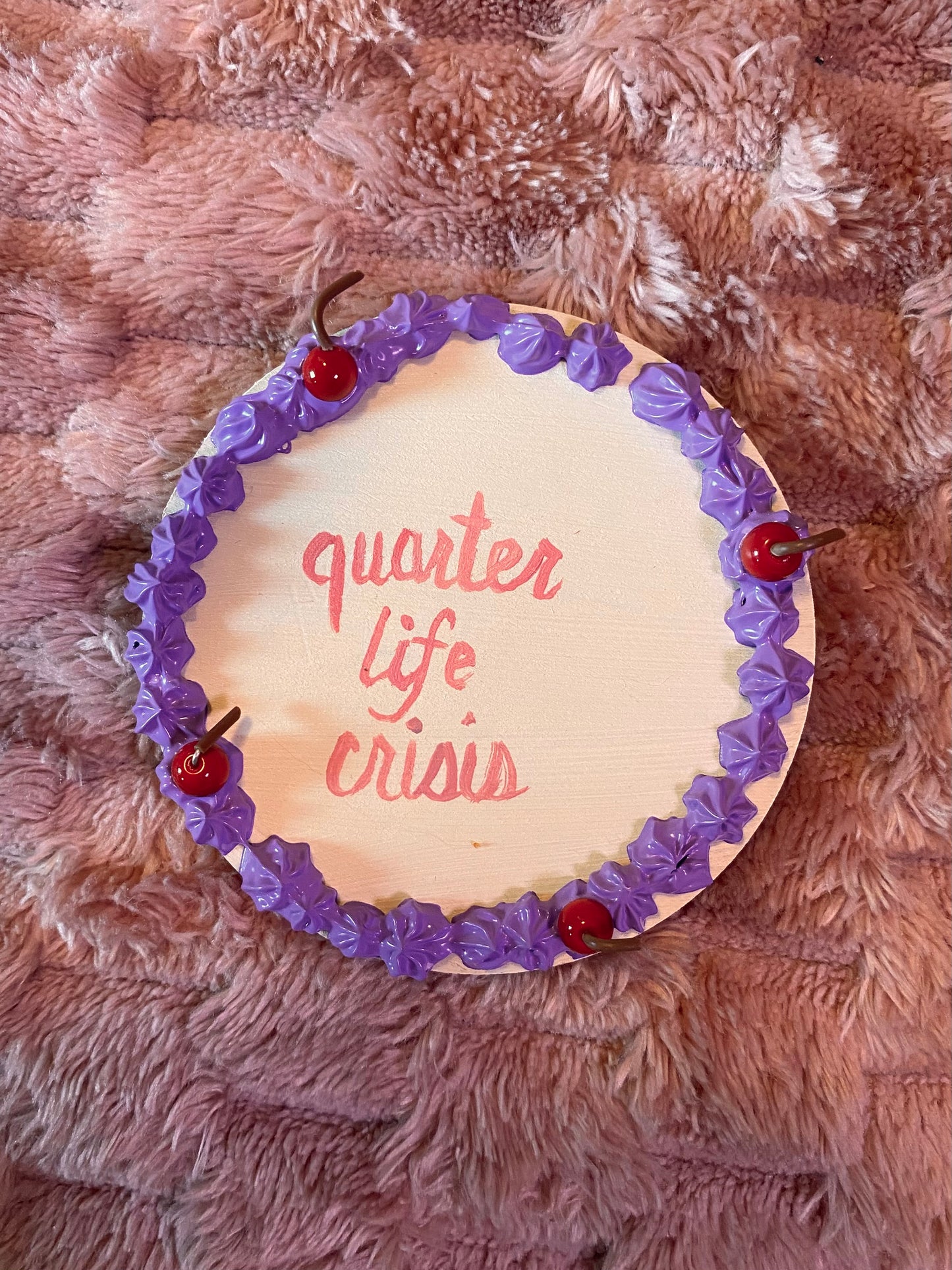 round disc decorated like a cake with "quarter life crisis" in the middle