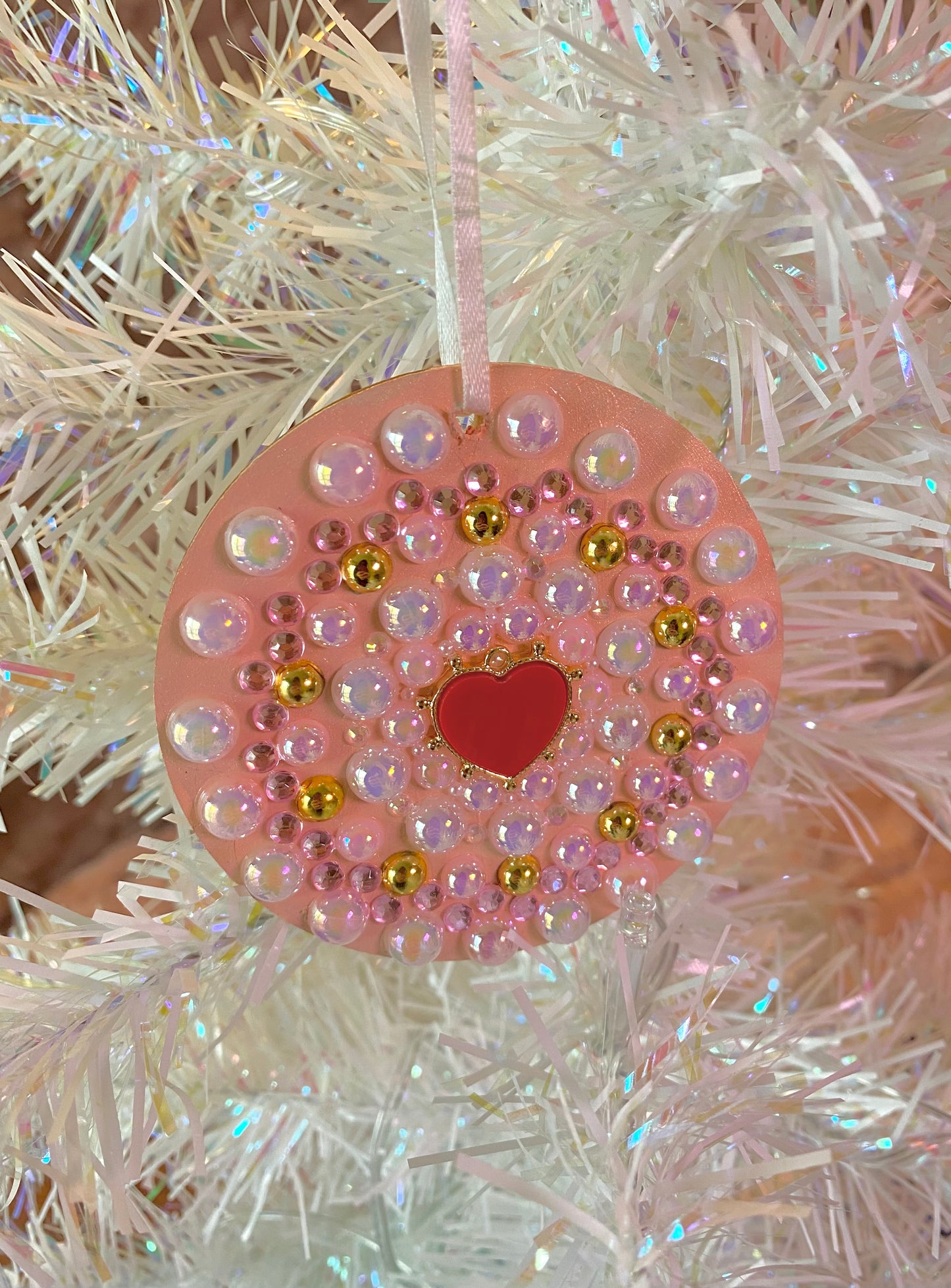 light pink round ornament with pearls and a red heart in the center