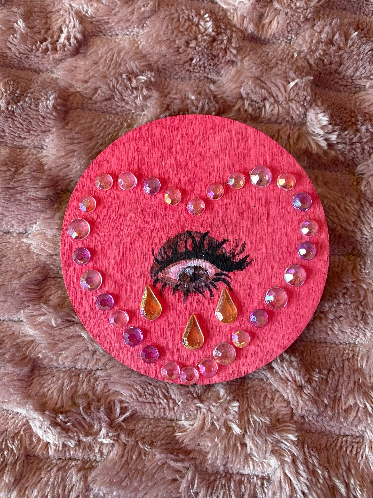pink round magnet with an eye inside a heart crying gemstones. 