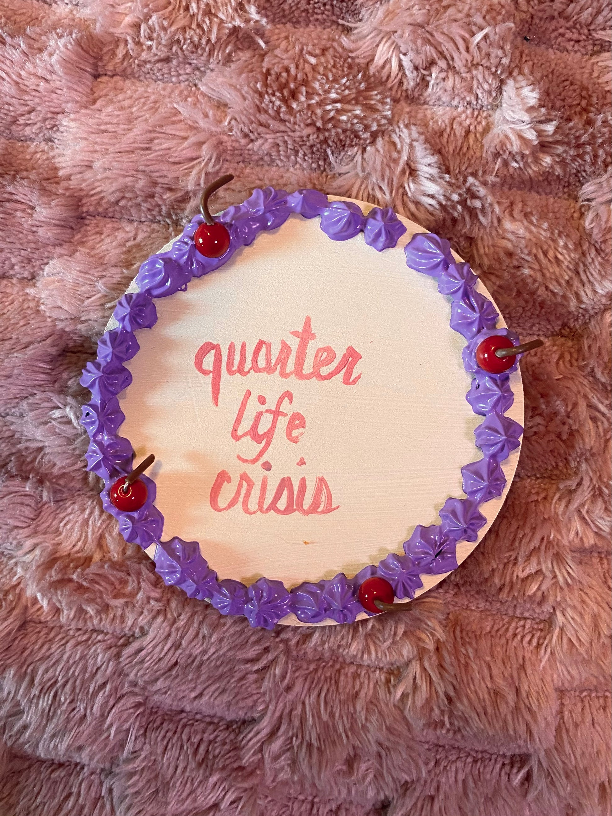 round disc decorated like a cake with "quarter life crisis" in the middle