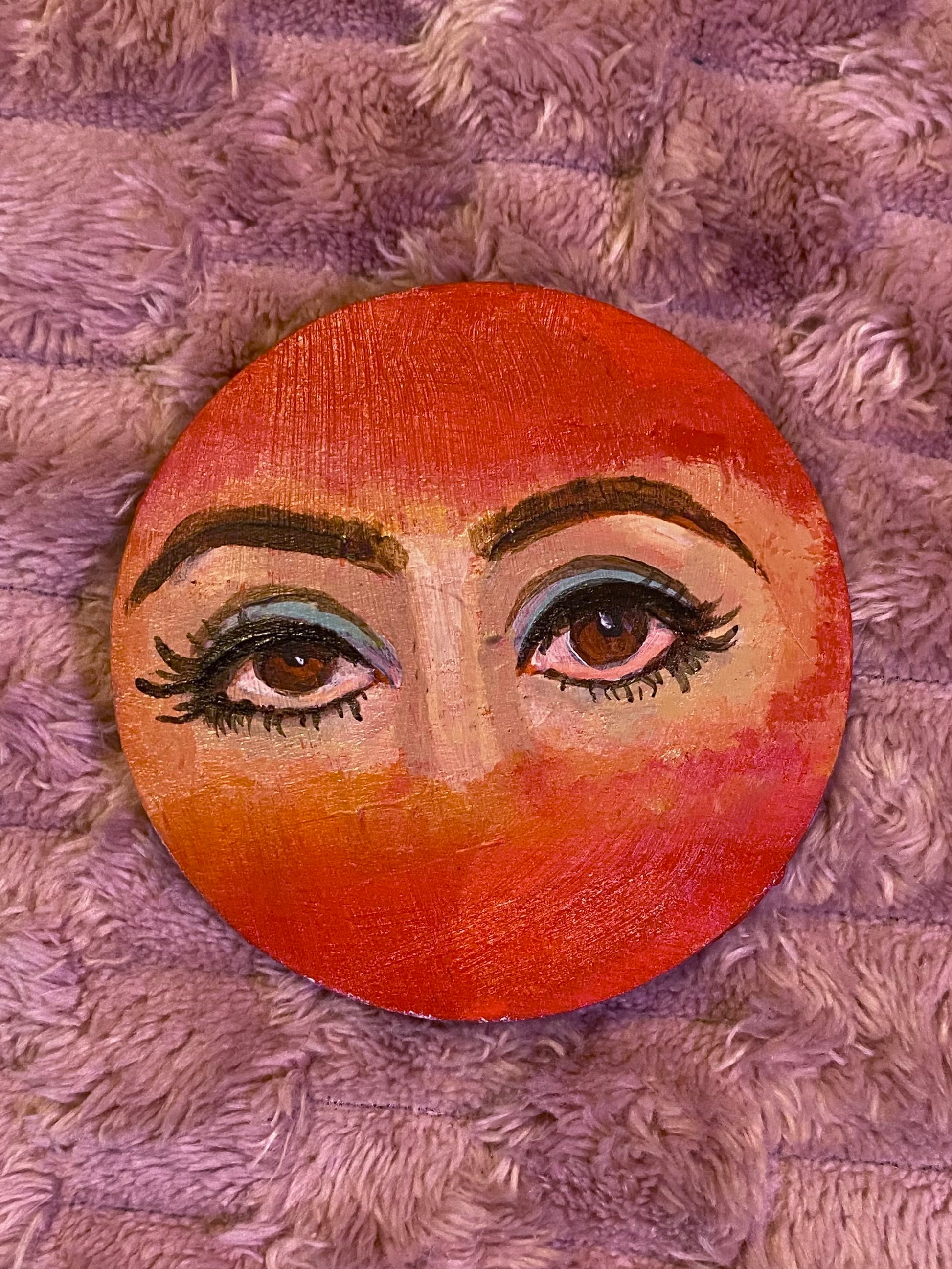 red disc with woman's eyes painted in the center