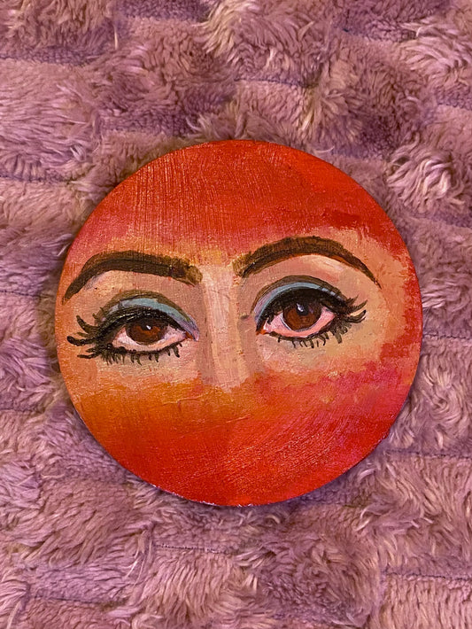 red disc with woman's eyes painted in the center